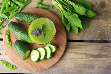 Glass of green healthy juice with spinach and cucumbers on table close up