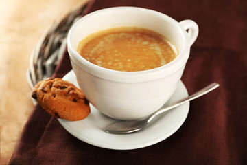 Cup of coffee with cookie on table, closeup