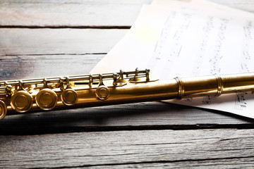 Obraz premium Silver flute with music notes on wooden table close up