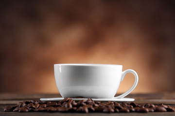 Cup of coffee and beans on blurred background