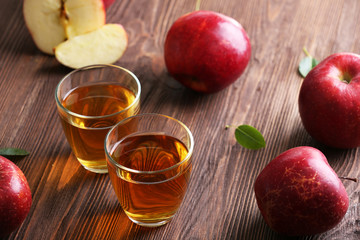 Glasses of apple juice and fruits on table close up