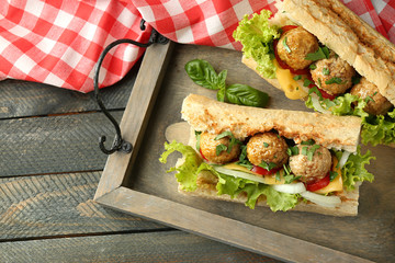 Homemade Spicy Meatball Sub Sandwich on tray, on wooden table background