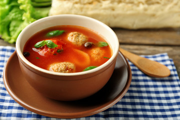 Tomato soup with meat balls on wooden spoon on wooden background