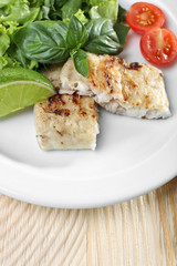 Dish of fish fillet with salad and lime on table close up