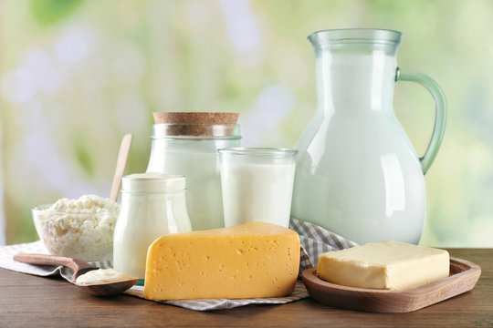Dairy products on wooden table, on green nature background