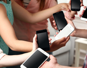 Many hands holding mobile phones close up