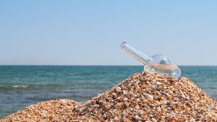 The open empty bottle lay on a hill of sand