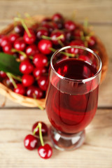 Glass of fresh juice with cherries on wooden table close up