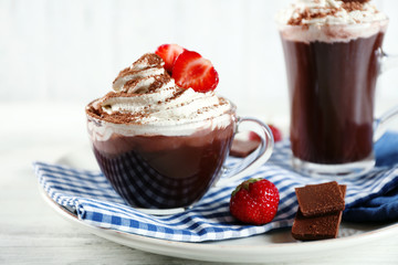 Cups of coffee with cream and fresh strawberry on color wooden background