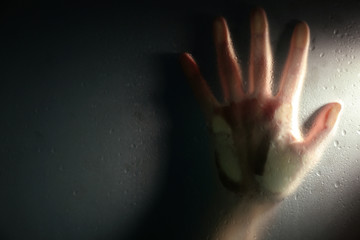 Female hand behind  wet glass, close-up