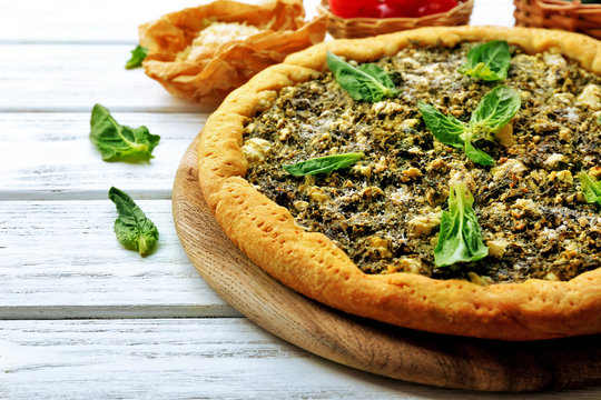 Open pie with spinach on table close up