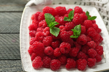 Sweet raspberries on plate on wooden  background