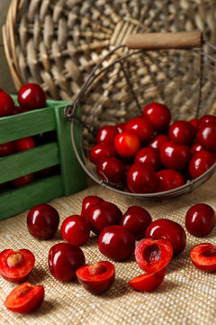 Sweet cherries with green leaves  in basket and wooden boxes, on wooden background