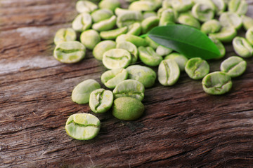 Pile of green coffee beans on wooden table, closeup