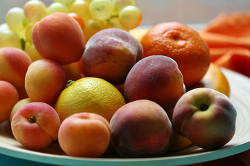 Heap of fresh fruits on tray on wooden table close up
