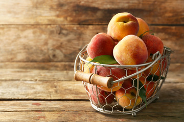 Ripe peaches in basket on wooden background