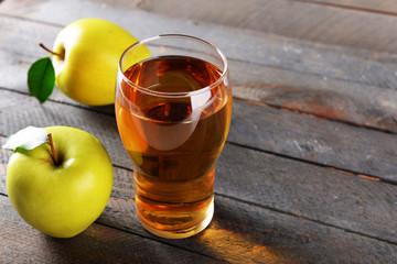 Glass of apple juice on wooden background