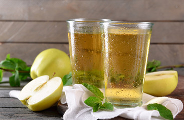 Wet glasses of apple juice on wooden background