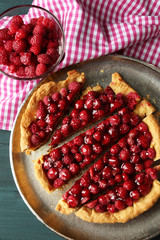 Tart with raspberries on tray, on wooden background