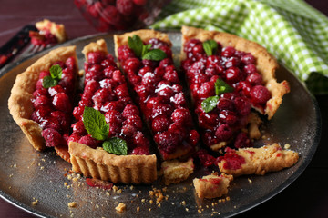 Tart with raspberries on tray, on wooden background