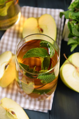 Glass of apple juice with fruits and fresh mint on table close up