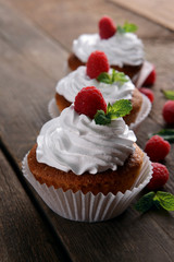 Delicious cupcakes with berries and fresh mint on wooden table close up