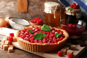 Tart with fresh raspberries, on wooden background