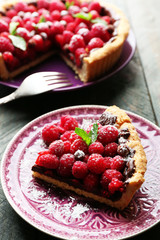 Piece of tart with fresh raspberries, on wooden background