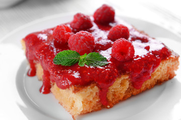 Fresh pie with raspberry jam in white saucer on wooden table, closeup