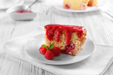 Fresh pie with raspberry jam in white saucer on wooden table, closeup