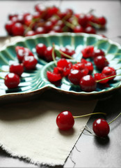 Sweet cherries on plate, on dark background