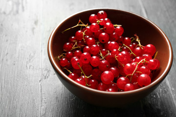 Ripe red currant  in bowl on wooden background