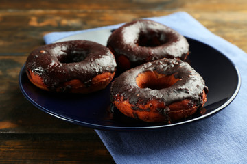 Delicious doughnuts with chocolate icing on table close up