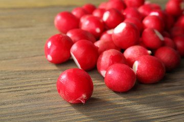 Heap of fresh radishes on wooden table close up background