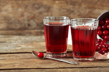 Two glasses with cherry juice on table, on wooden background