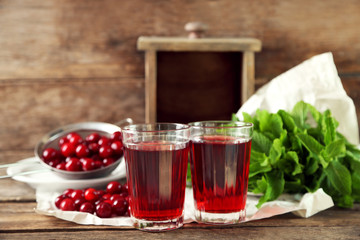 Two glasses with cherry juice on table, on wooden background