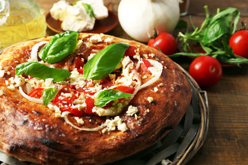 Greek homemade pizza with ham,onion, roasted tomato, creamy feta on wooden table background