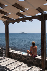 Girl on a beach in Santorini, Greece, looking to the horizon