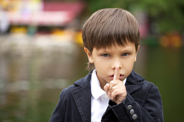 Little boy has put forefinger to lips as sign of silence