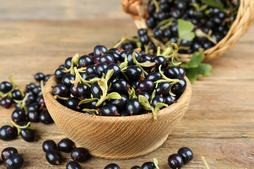 Fresh black currants in bowl on wooden table, closeup