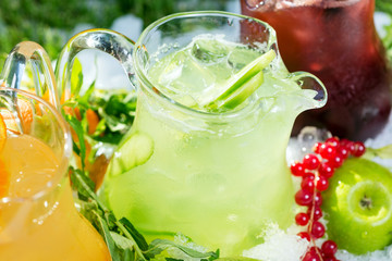 a mix of several bright colored delicious cold lemonade carafes of cucumber and orange and basilon with creative composition