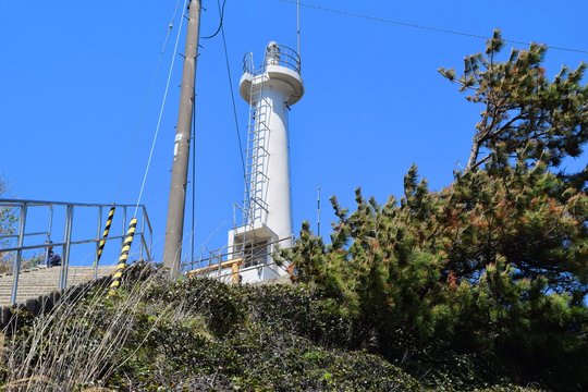 荒崎灯台(海上保安庁 酒田海上保安部)／山形県鶴岡市にある荒崎灯台を撮影した写真です。荒崎灯台は白亜円形の小型灯台で加茂水族館近くの断崖絶壁に建っています。周辺は庄内海浜県立自然公園に指定され日本海を望む風光明媚の地です。灯塔高（地上から塔頂まで）は12.4m、標高（平均海面～灯火）は33mで、光度は5600カンデラ（実効光度）、光達距離は12.5海里（約23km）の灯台です。