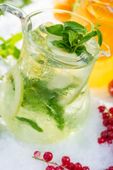 a mix of several bright colored delicious cold lemonade carafes of cucumber and orange and basilon with creative composition