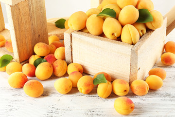 Ripe apricots in crate on wooden table, closeup