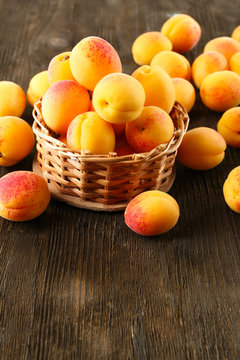 Ripe apricots in wicker basket  on wooden background