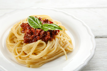 Spaghetti Bolognese on white plate, on color wooden background