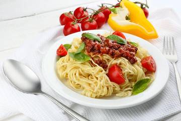 Spaghetti Bolognese on white plate, on color wooden background