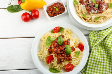 Spaghetti Bolognese on white plate, on color wooden background