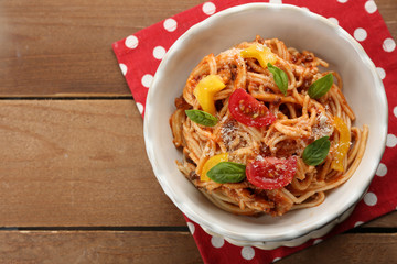 Homemade Spaghetti Bolognese with parmesan cheese in white bowl, on color wooden background