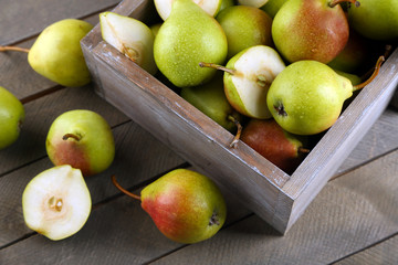 Ripe pears in wooden box on table close up